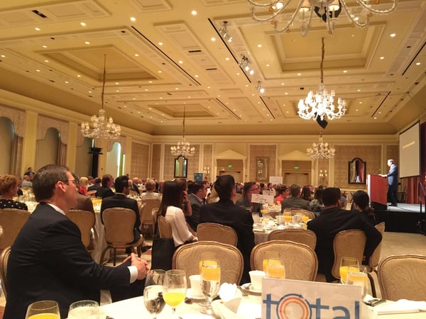 large room with audience and dining tables at Palm Beach Chamber for Cybersecurity with Brad Deflin speaking at podium