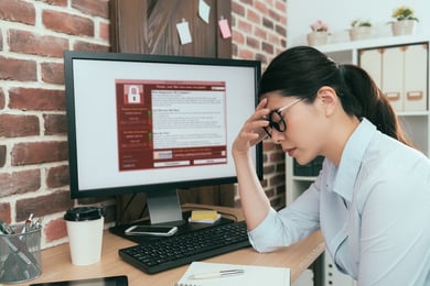 woman at desktop locked by ransomware attack