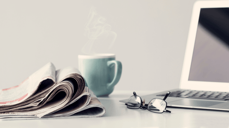 newspapers laptop and coffee green cup