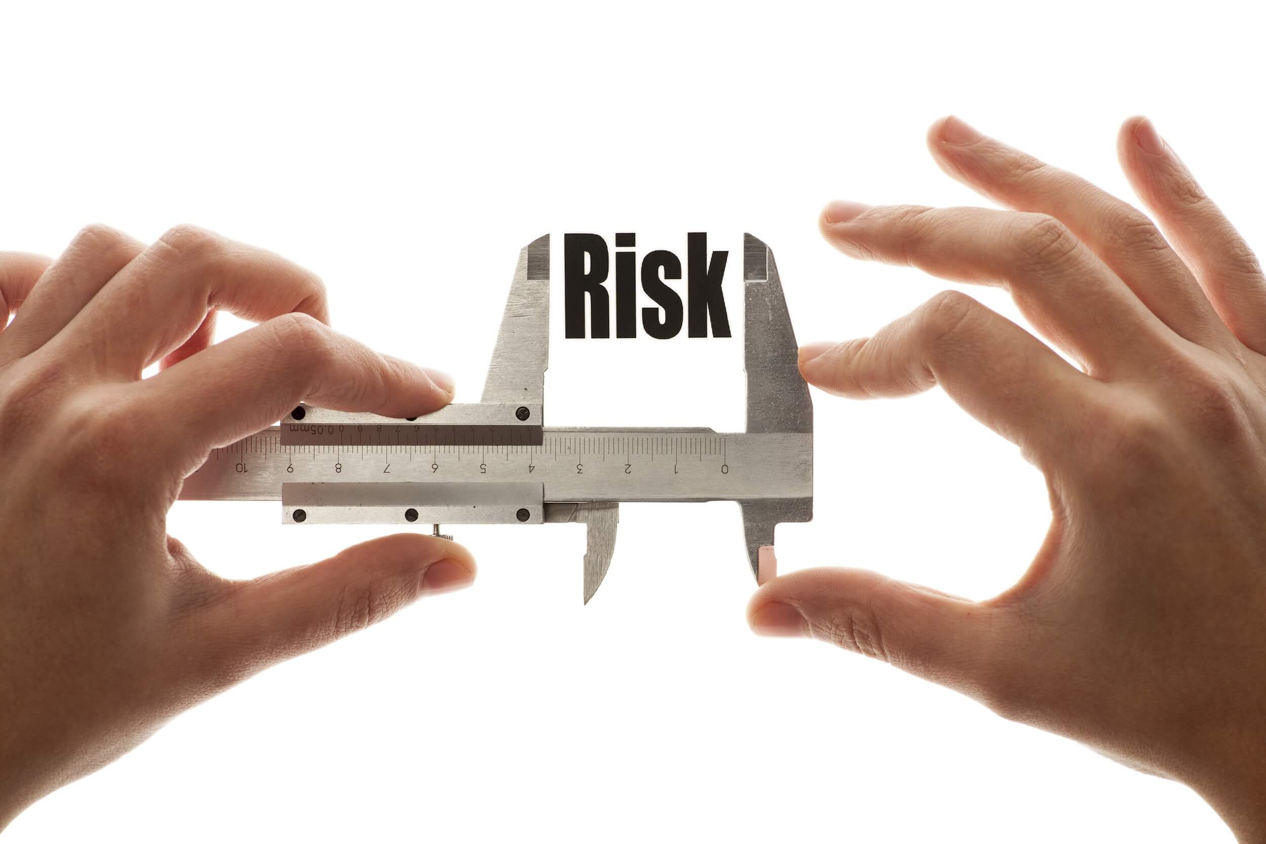 two hands holding up a precision measuring instrument with RISK spelled out