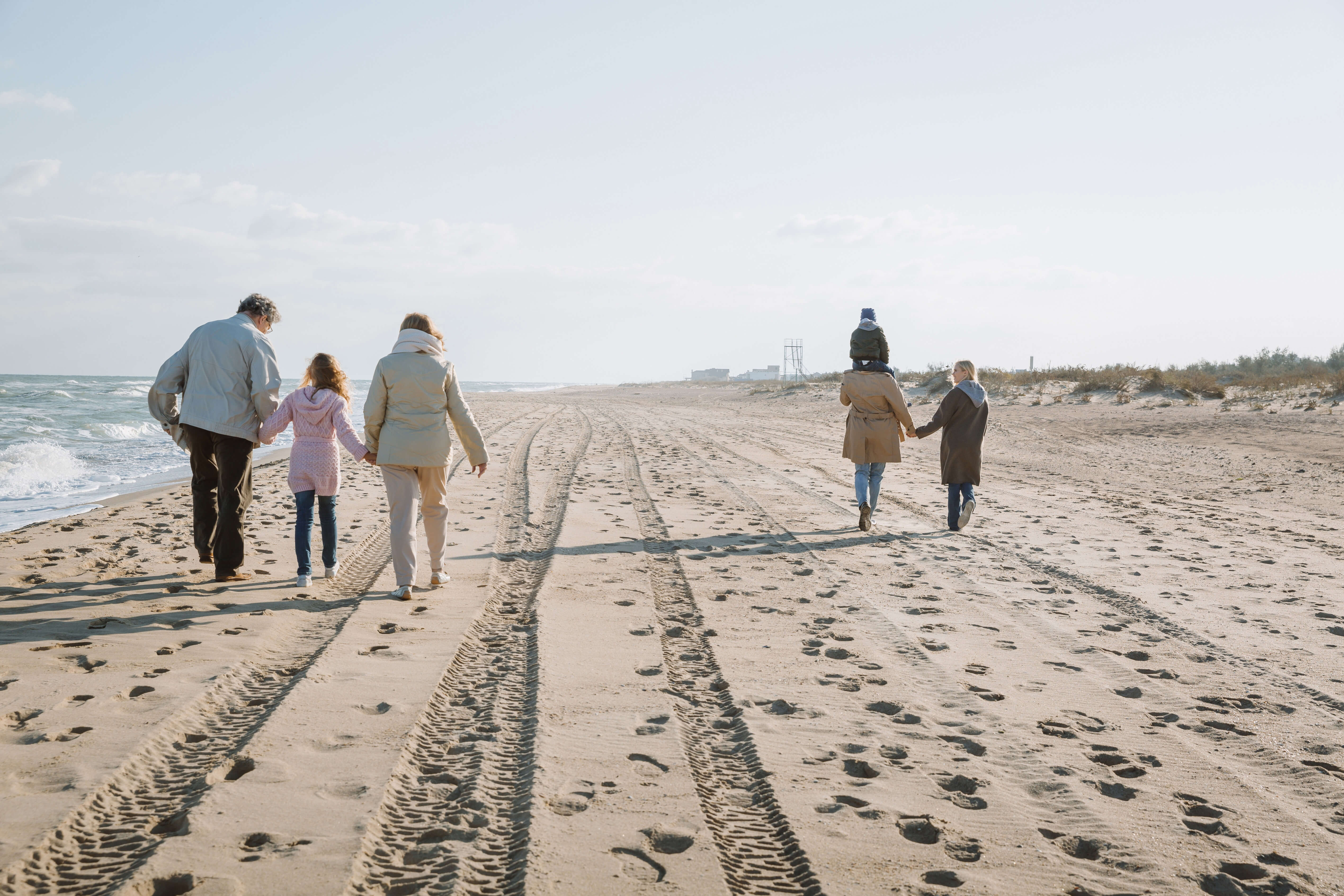 multigenerational family walking on beach 