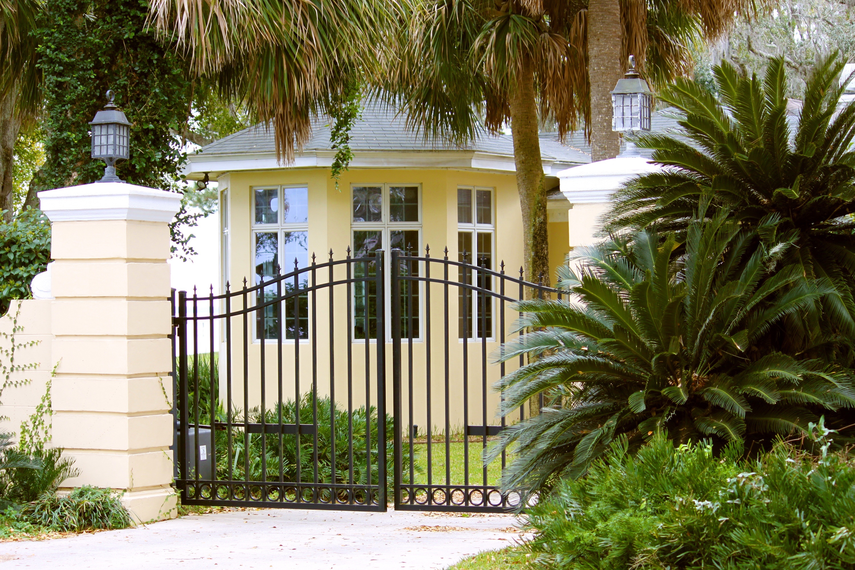 a black wrought iron gate and the entrance of a yellow home