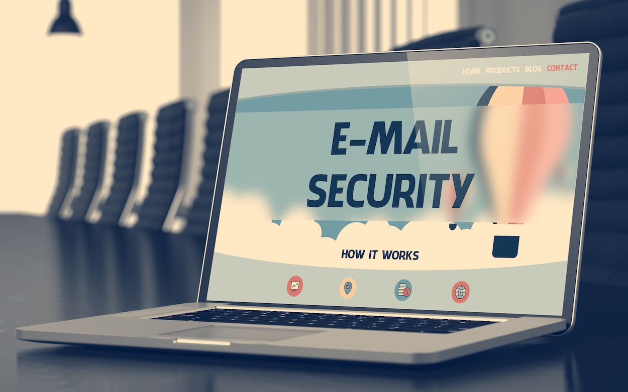 an open laptop with screen displaying "Email Security" on a long conference table surrounded by empty chairs