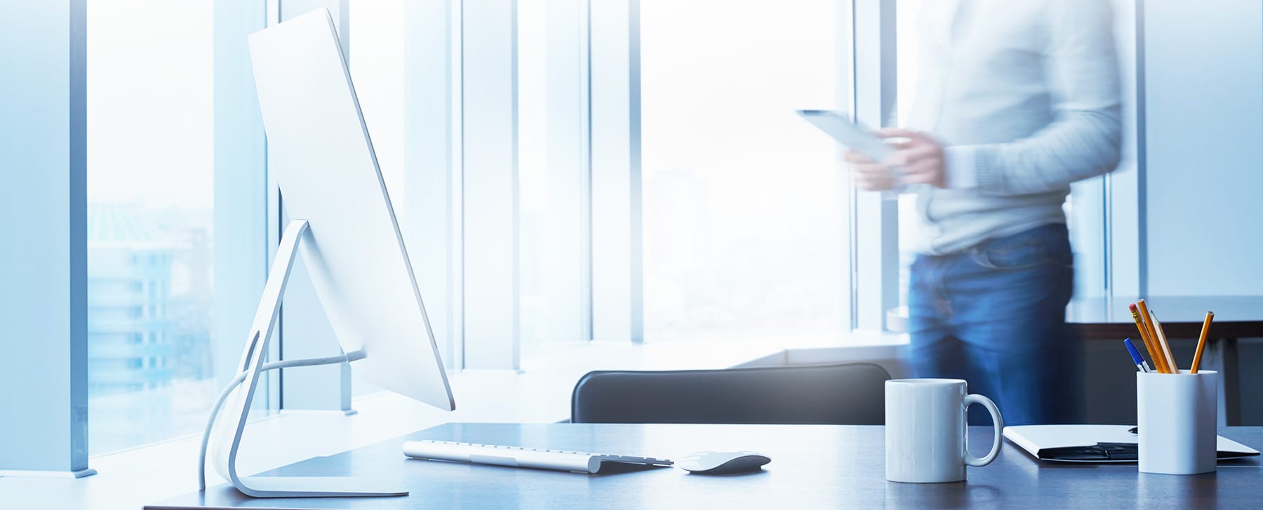 white sun lit office space with white coffee cup and person with a real estate closing document