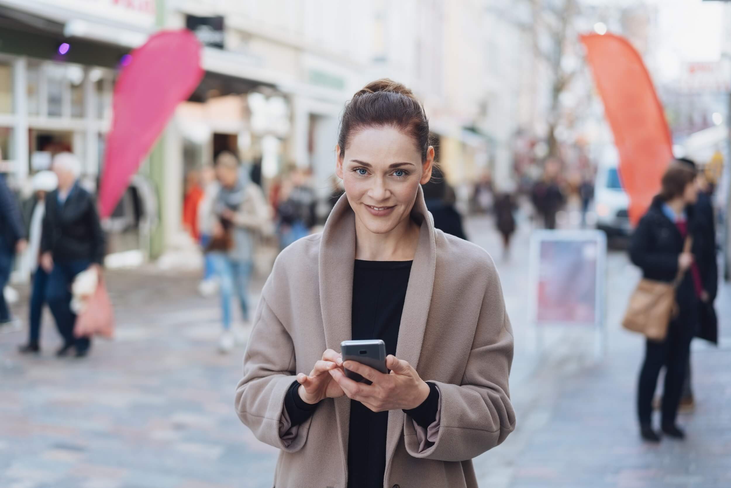 woman with phone using a VPN for privacy while walking on a cobbled sidewalk 